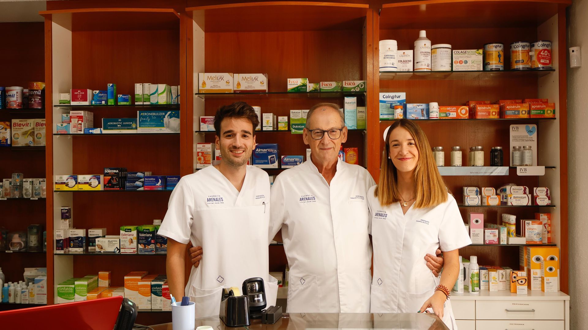 Una farmacéutica está de pie en una farmacia con los brazos cruzados.